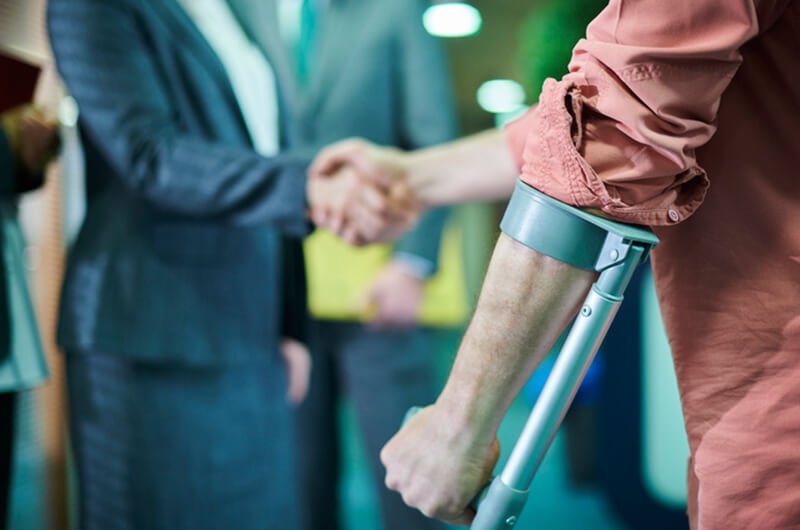man on crutches shaking agent hand - insurance settlements - insurance planning farmington ct
