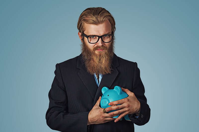 young stingy man with piggy bank - be frugal not cheap - financial planning services farmington